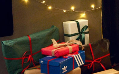 Colorful gift boxes wrapped in festive ribbons and strings, surrounded by twinkling lights, creating a cozy and celebratory atmosphere.