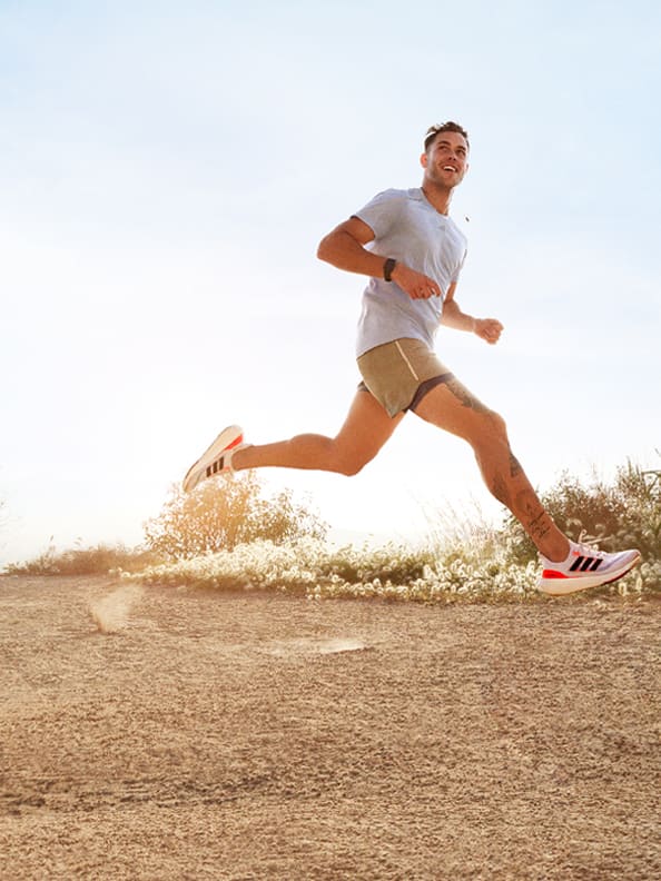 Image of man running outdoors wearing Ultraboost Light and adidas running gear.