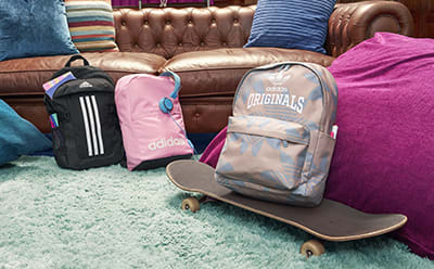 Three backpacks in front of couch inside school building