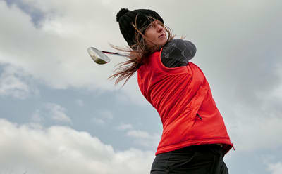 Women swinging a golf club.