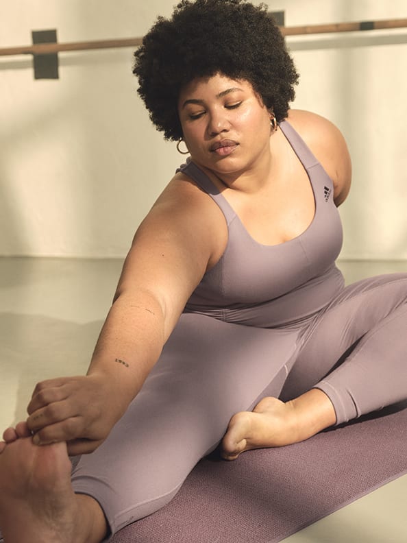 Image of the back of a plus-sized model stretching wearing a lavender supportive bra