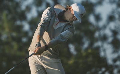 Man swings a golf club in golf jacket