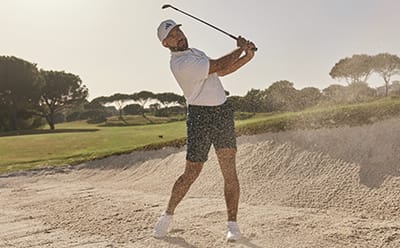 Man in bunker wearing golf shorts