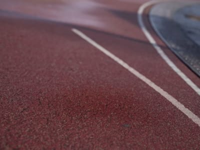A red running track with a white line running through the center, with a blurred background.