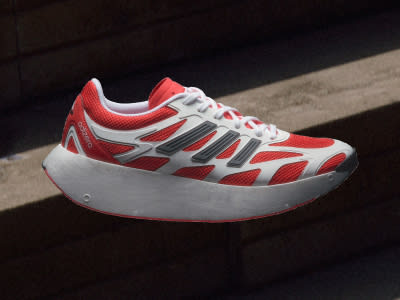A red and white athletic shoe with a thick platform sole sits on a dark surface, casting a shadow against the background.