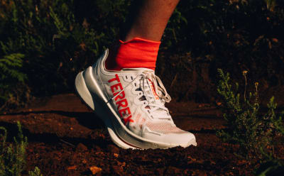 Close up of athlete’s foot wearing adidas Agravic trail running shoe while running outdoors. 