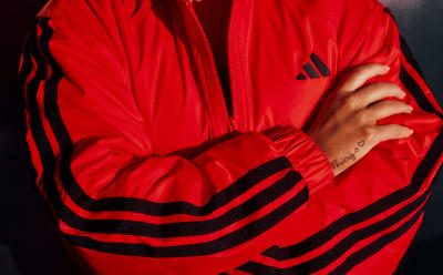 A close-up view of a person's torso wearing a bright red and black striped jacket or hoodie, with the person's hand visible in the foreground.