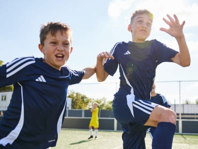 Two boys jumping in the air during football practice