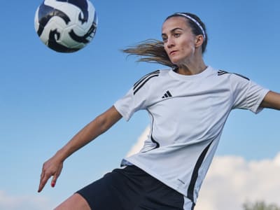 Female player kicking an adidas ball while wearing Predator boots