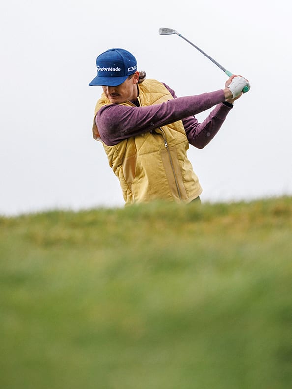 Man swings golf club.