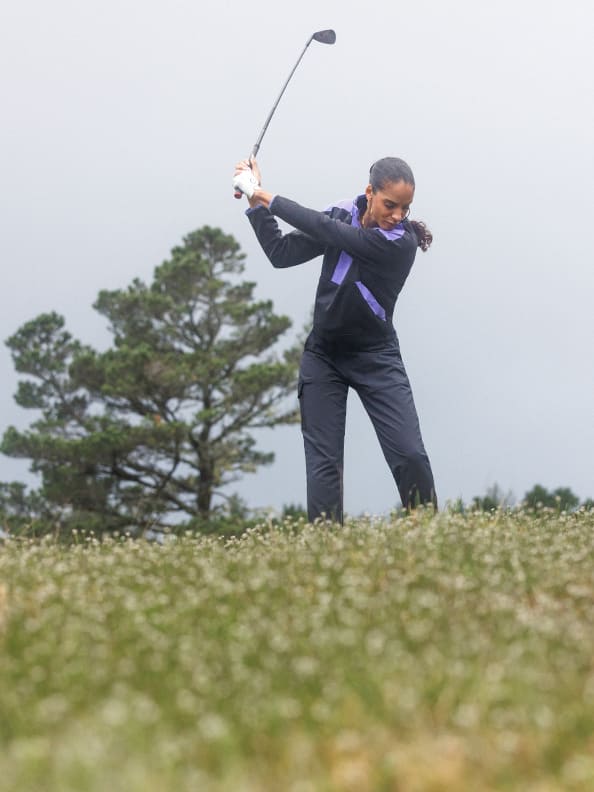 Woman swings golf club.