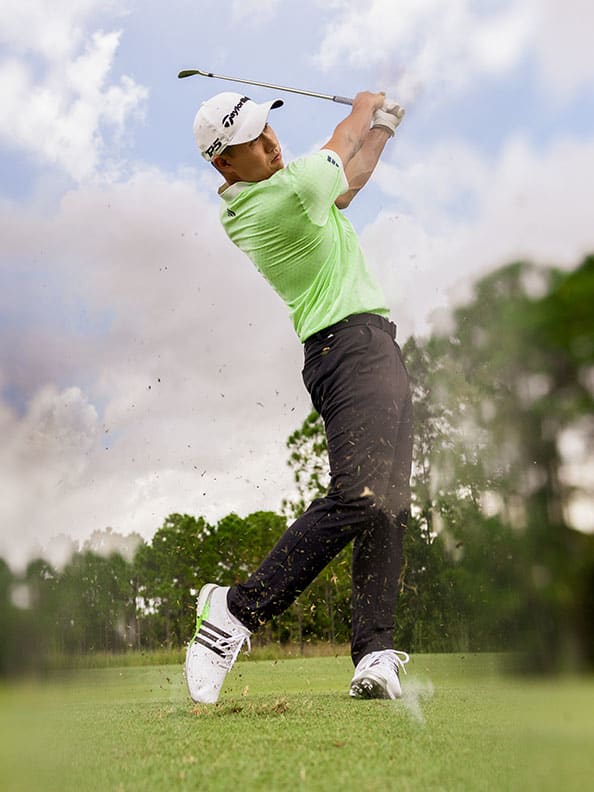 Collin Morikawa swings a golf club on a golf course.