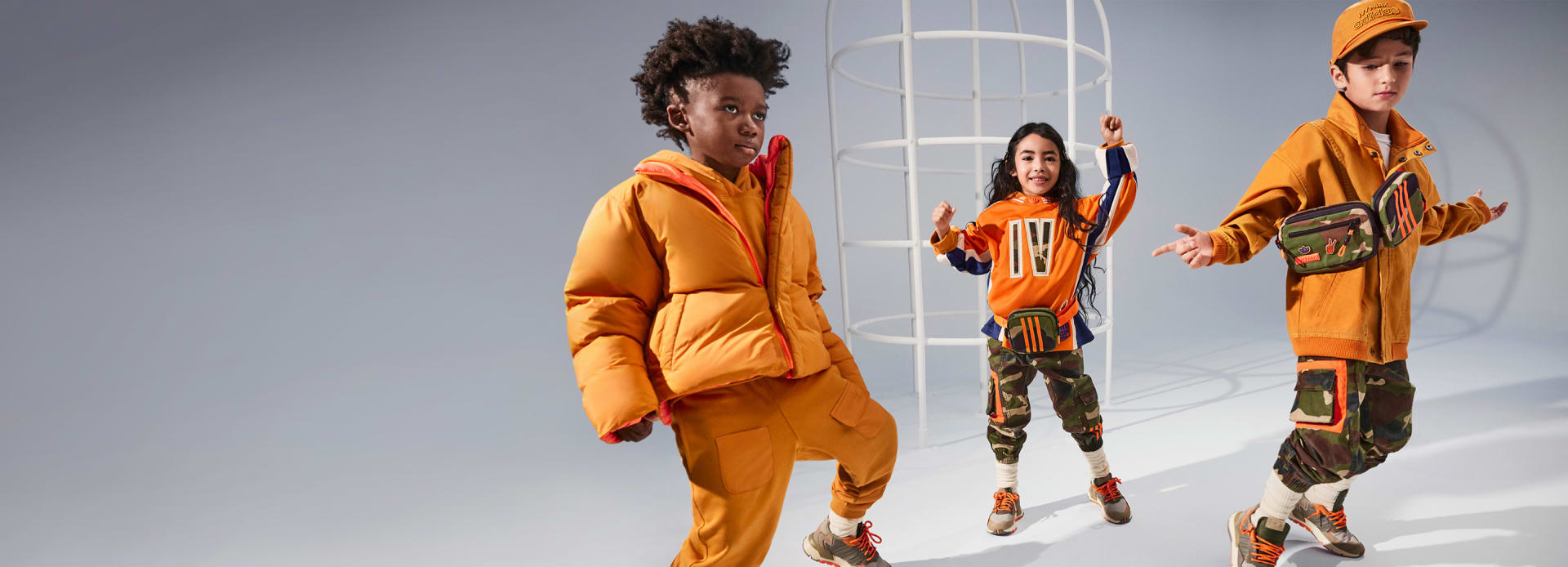 3 young models are photographed posing actively in the adidas x IVY PARK collection against a grey backdrop.