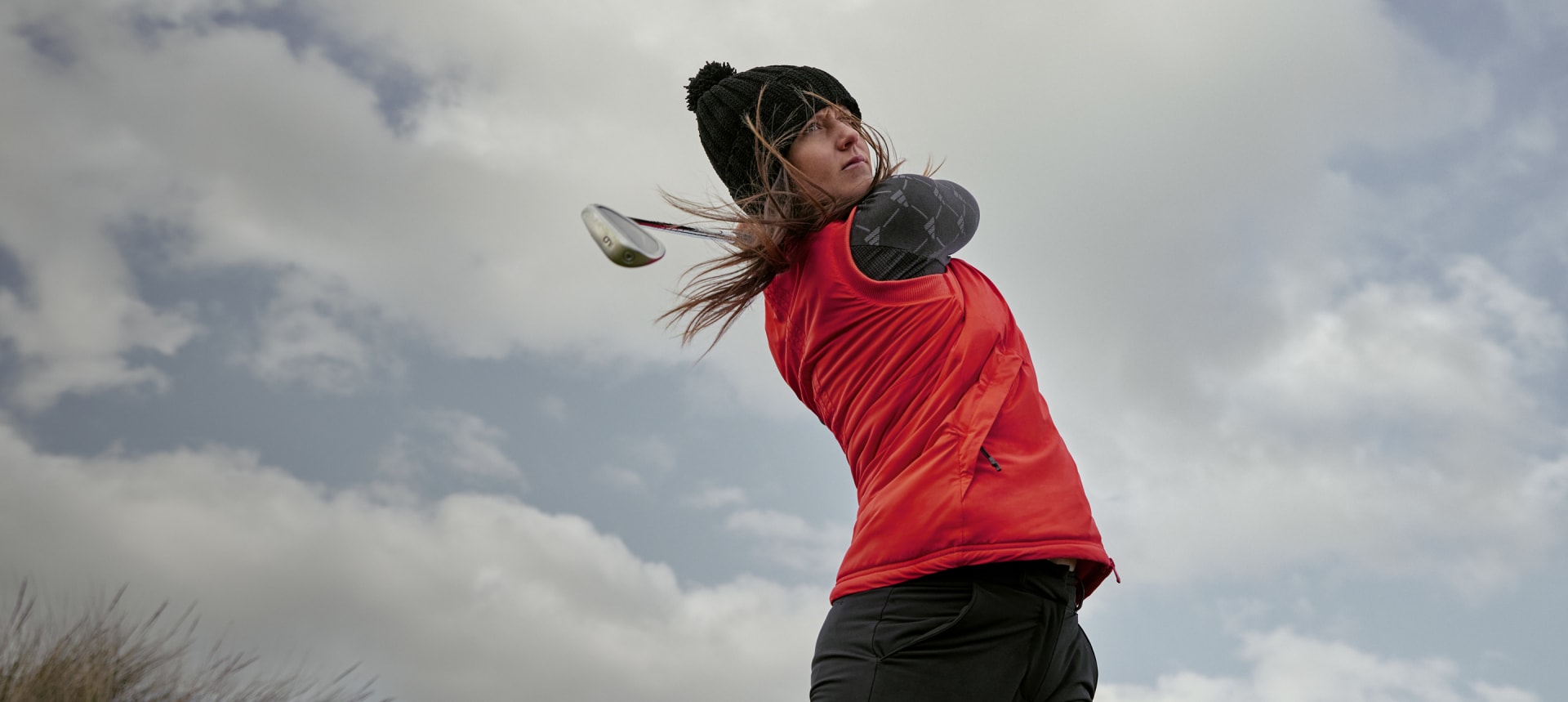 Linn Grant swings a golf club in cold weather apparel.