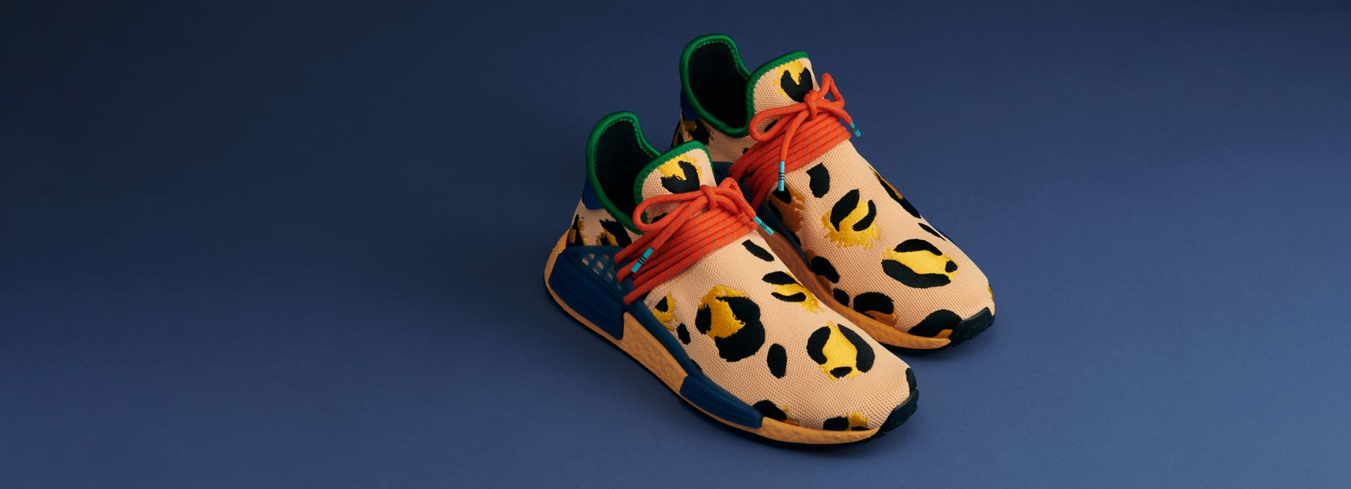 Aerial view of pair of amber animal print shoes on blue background.