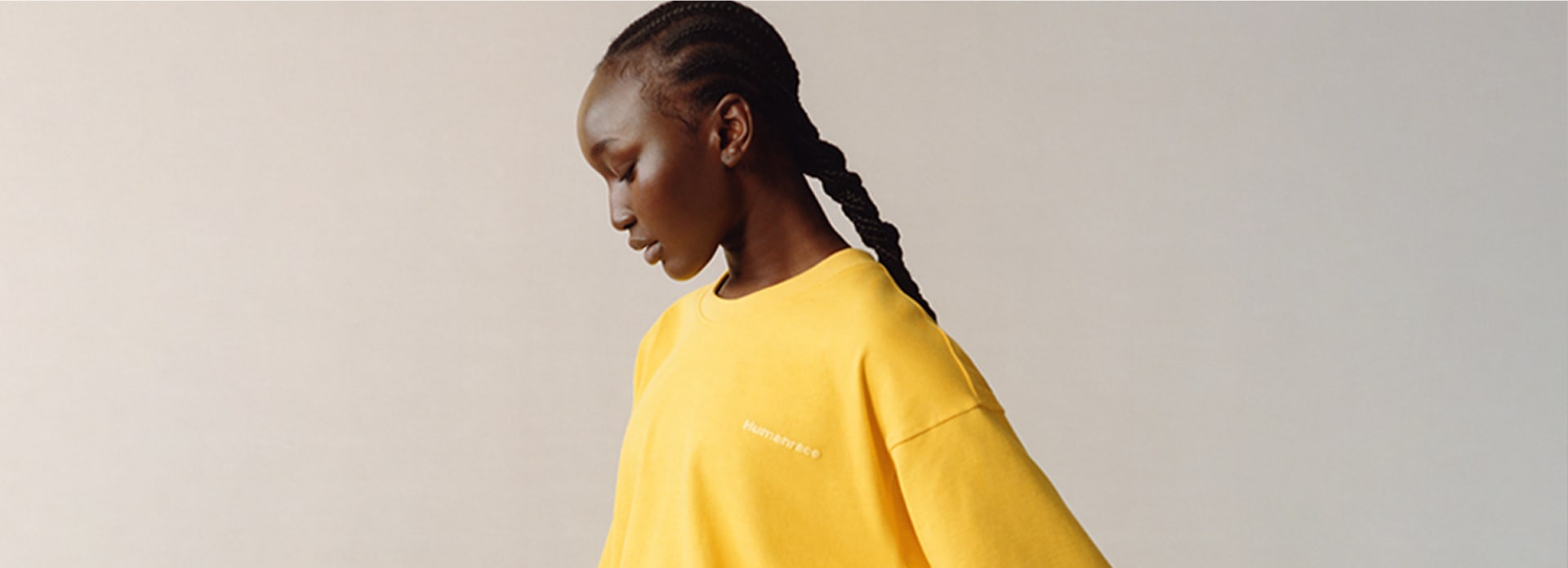 Woman wearing a yellow sweatshirt from the Pharrell Williams Premium Basics collection