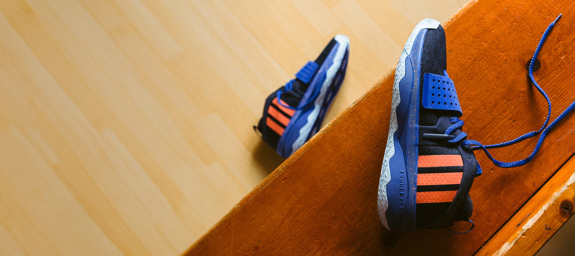 Two blue and orange basketball shoes lie on their side on sports court