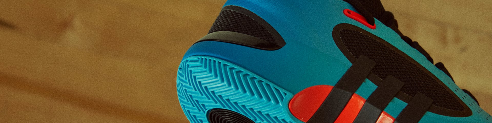Close-up shoe of blue, black and orange basketball shoe heel and sole, with adidas three-stripes