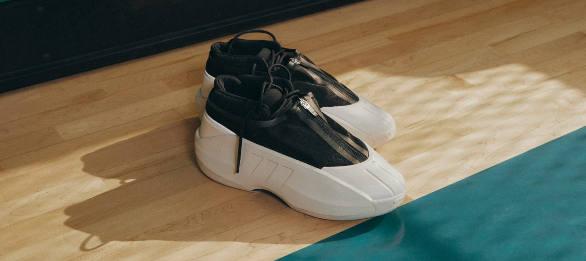 Black and white shoes rest on edge of court in dappled light