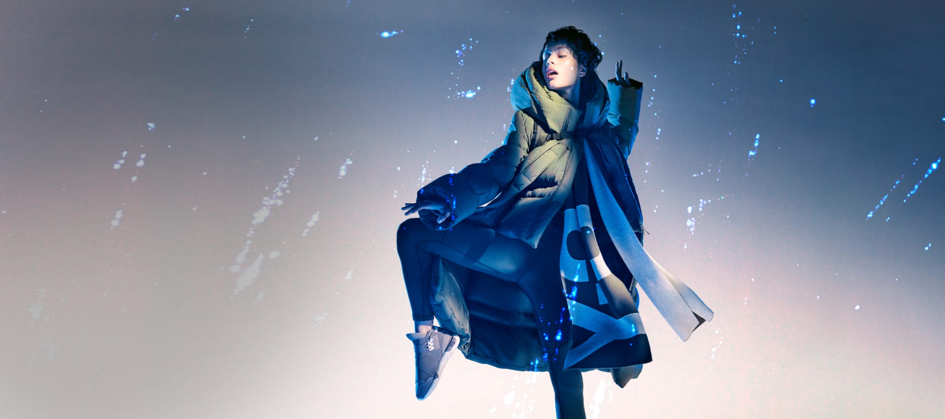 A woman dances passionately in an adidas Y-3 puffer jacket and sneakers while the rain falls around her.