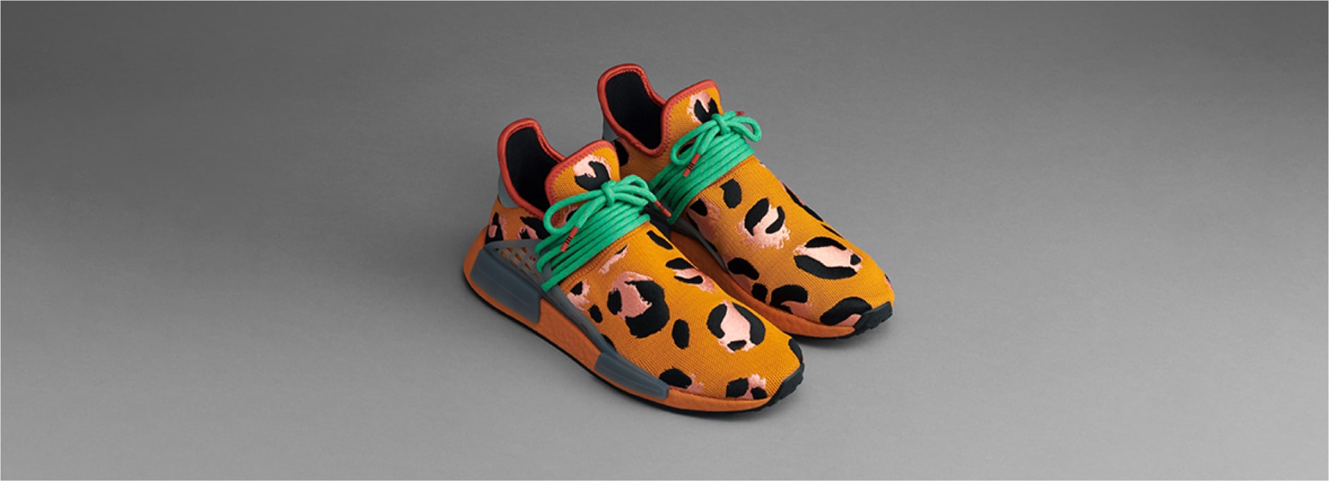 Pair of orange Hu NMD Animal Print shoes against gray background