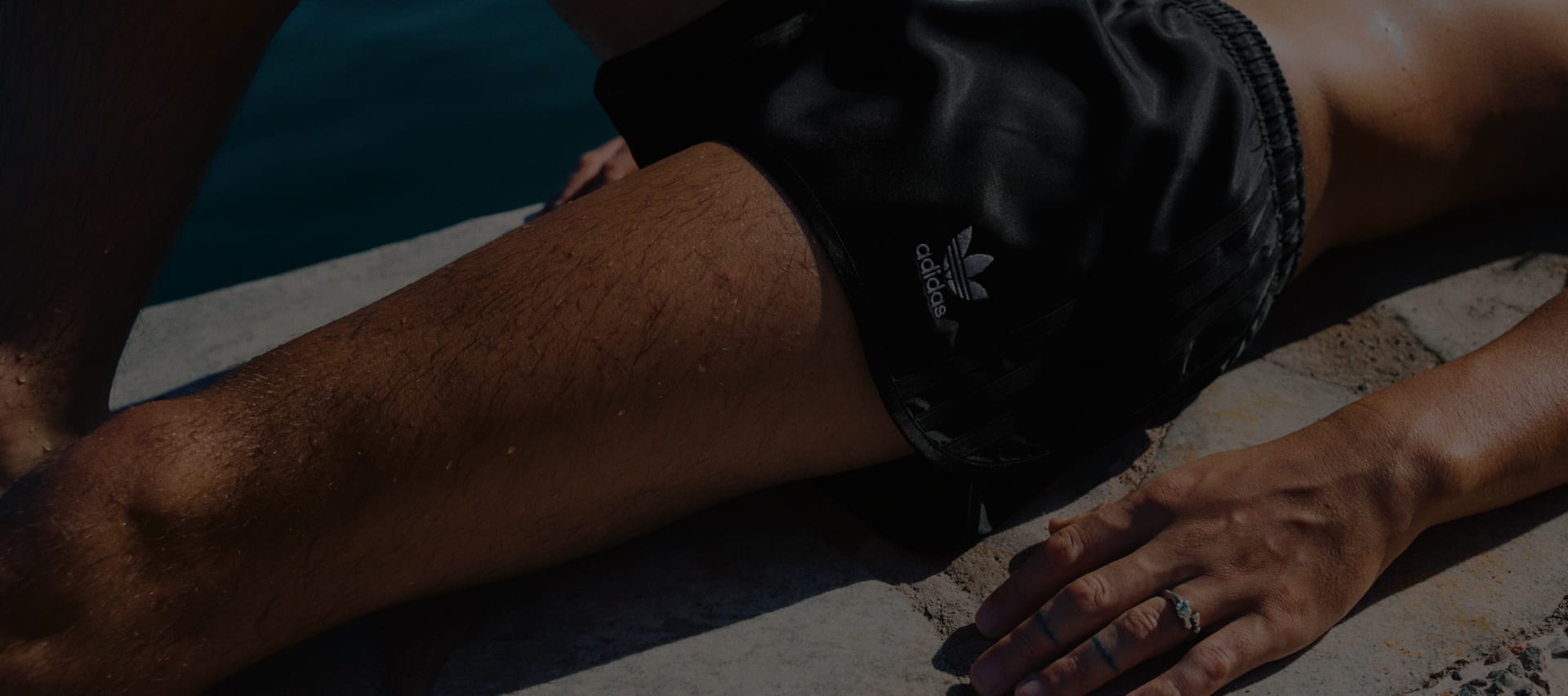 The image shows a close-up view of a person's lower body, with a black clothing item covering the legs and hands resting on the thighs.