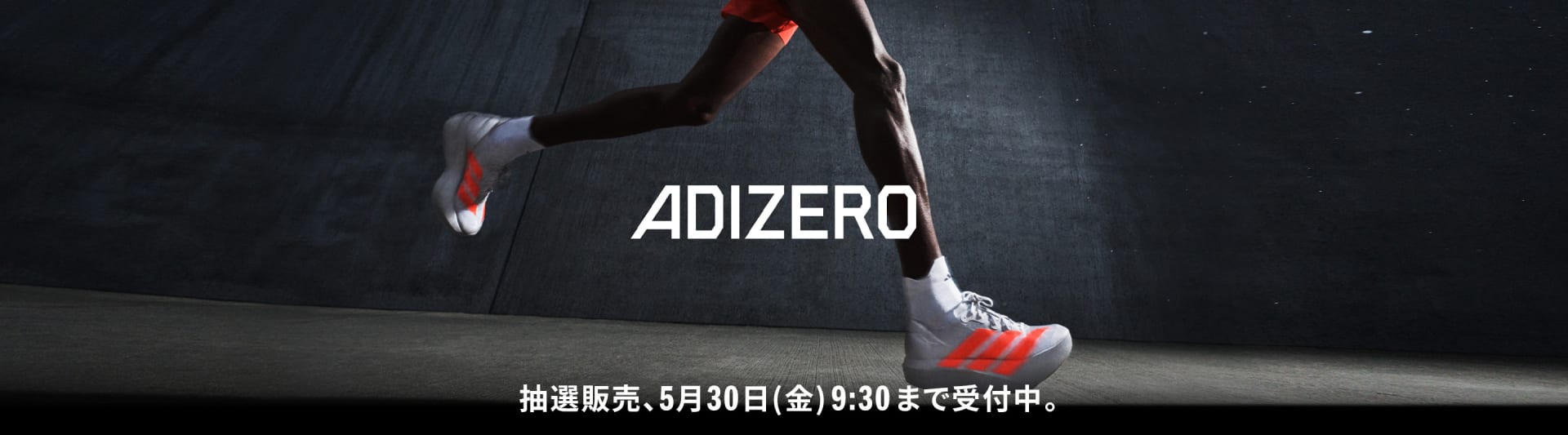 A person's legs and feet wearing athletic shoes with the word "ADIZERO" prominently displayed on a dark background.