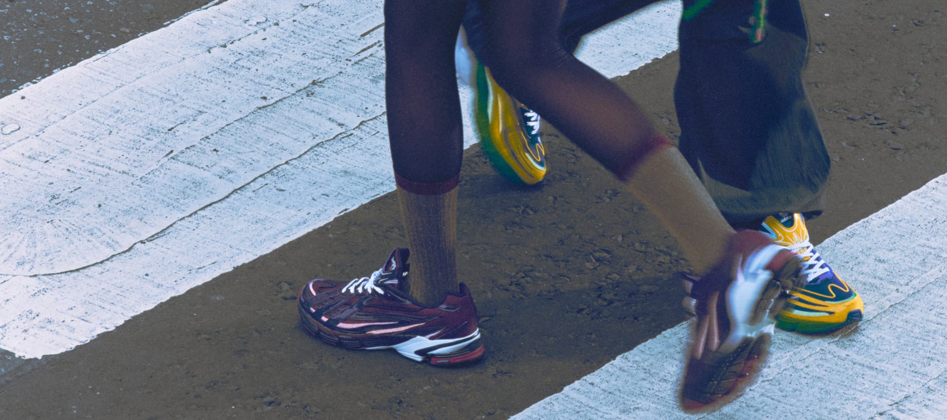 The adidas BAPE Orketro in yellow, green, and blue, plus the pink and purple version, pictured on-foot at a street crossing.