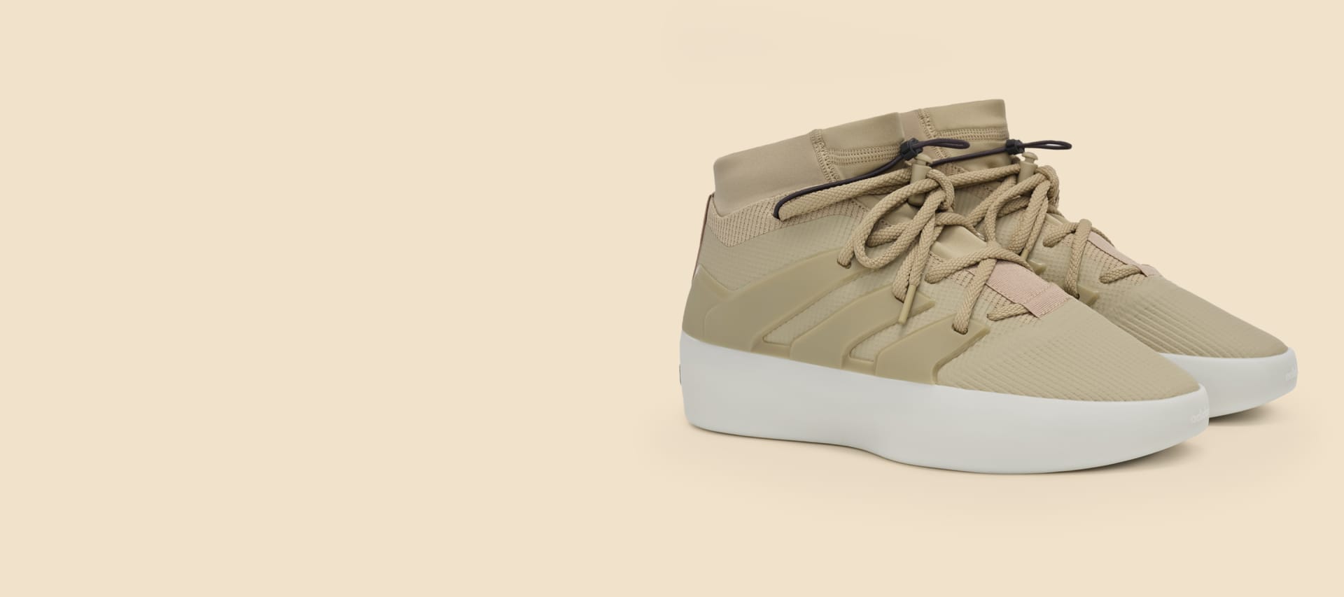 Beige shoe with white sole on cream background.