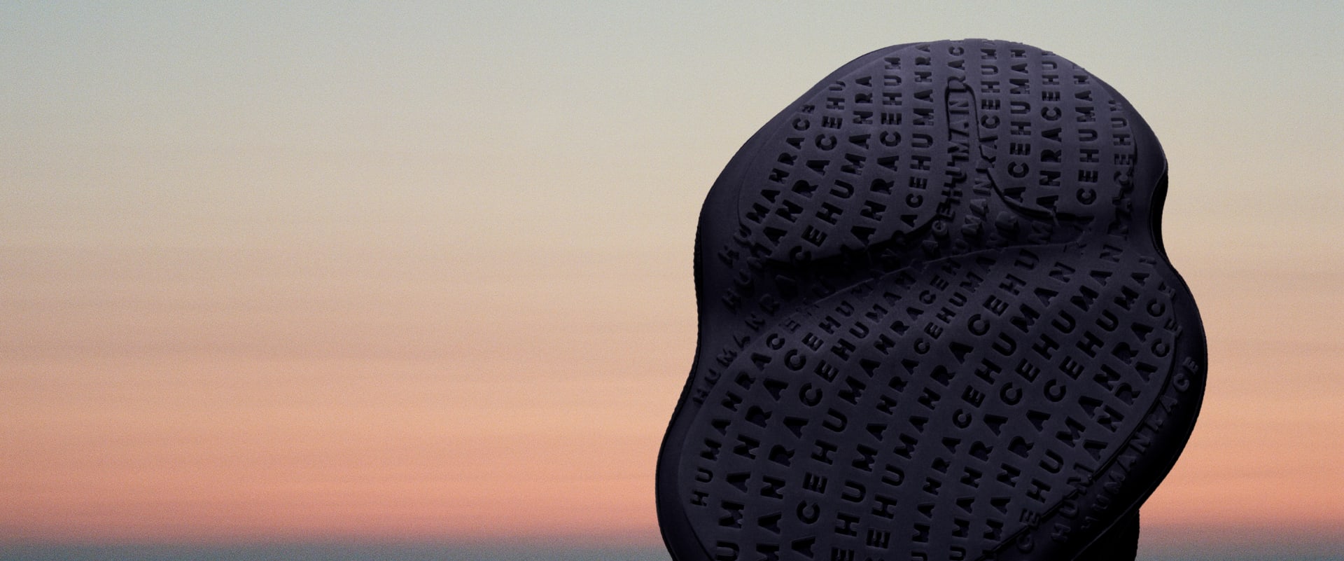 The outsole of a black Humanrace Sičhona shoe against the backdrop of a tinted sky.