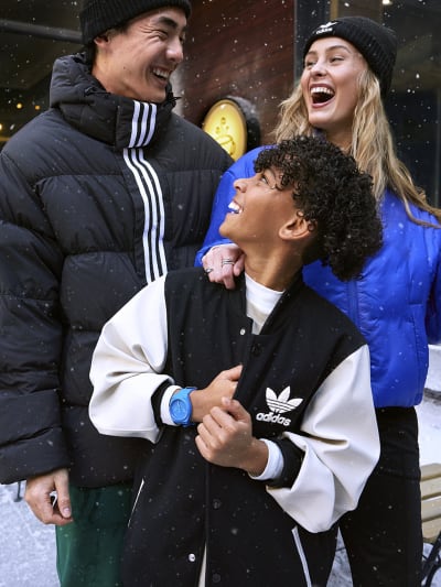 Image of a man, woman and kid wearing adidas winter apparel and laughing in the snow.