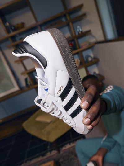 Image of a man holding up an adidas sneaker to the camera.
