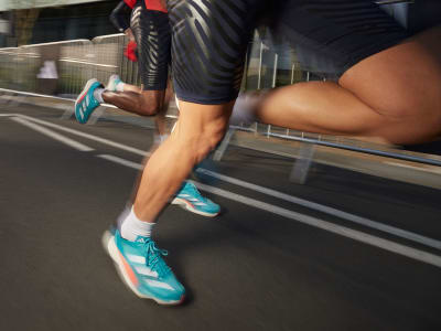Close up of athletes' legs wearing Adizero running shoes. 