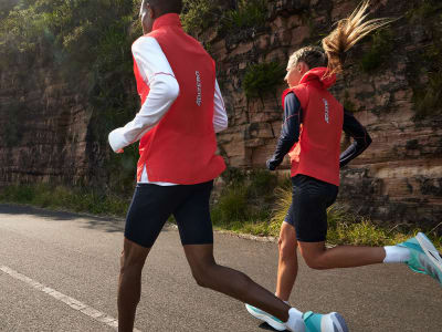 Man and woman running outside is red adizero vests and adizero shoes.