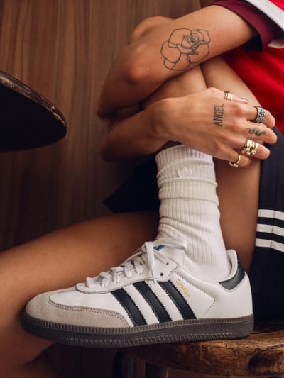 Female model wearing adidas Sambas with her foot in a chair. 