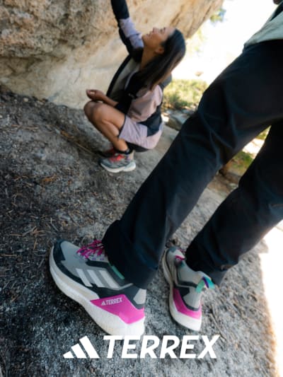 Image showing a person wearing the new Free Hiker 2.0 GORE–TEX, with a female in the background wearing shoes and clothes from the TERREX range.