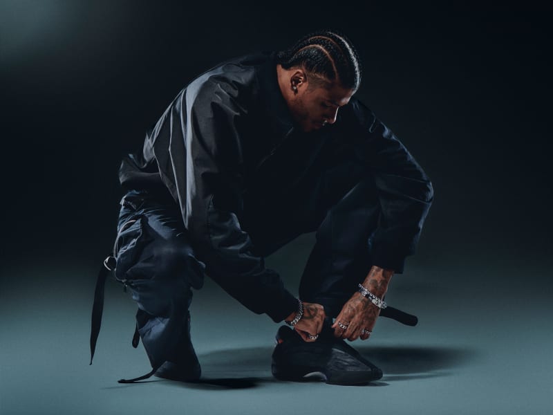 Person crouching to adjust black basketball shoe.