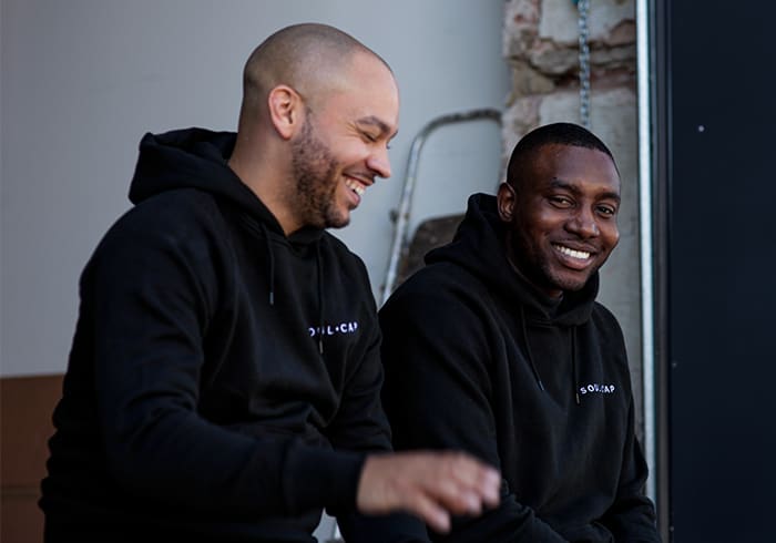 two people sat down in black hoodies laughing