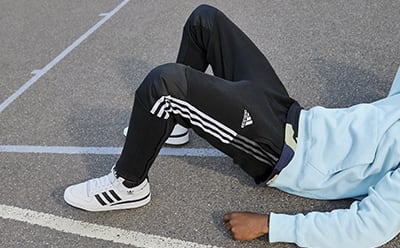 Close up of man lying down on sports gym floor, wearing track pants.