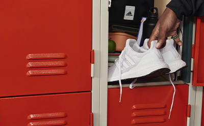 Close-up image of adidas shoes being put into a school locker