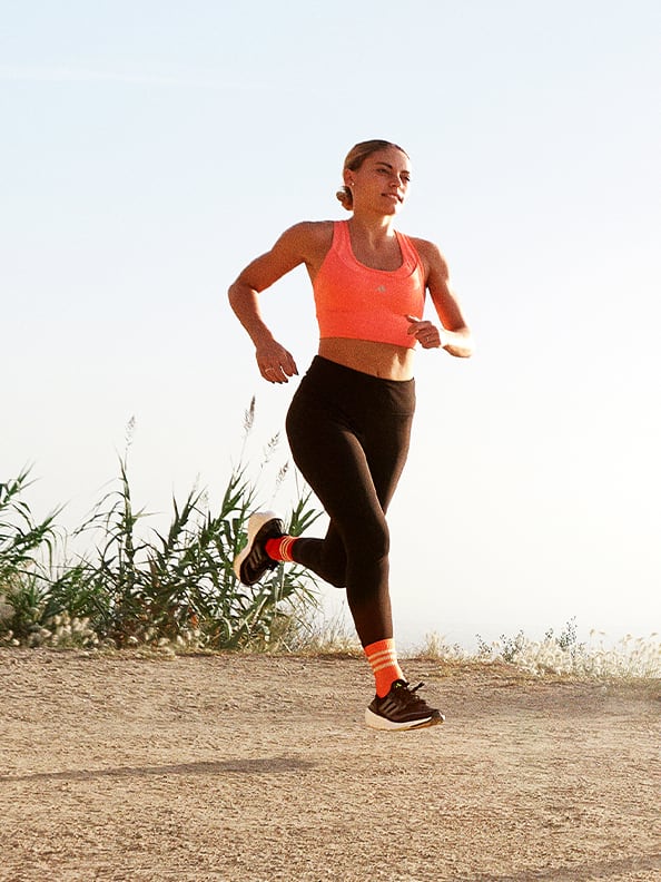 Image of woman running outdoors wearing Ultraboost Light shoes and adidas running gear.