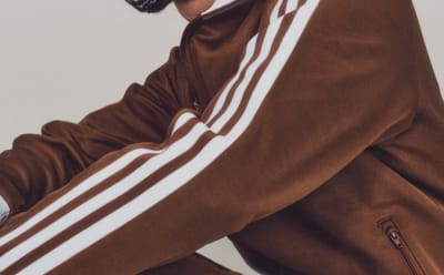 Close-up of a person's arm in a brown Beckenbauer tracksuit with white stripes.