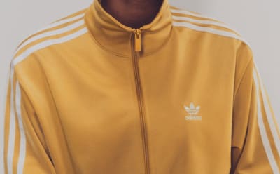 Person in a mustard yellow Firebird jacket with white stripes on the sleeves and a high collar.