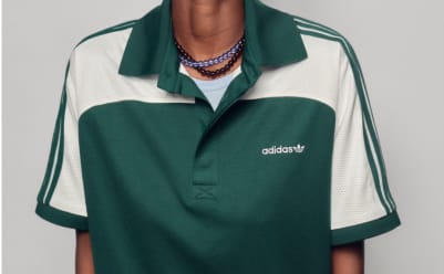 Close-up of a person's shoulder in a cream Adidas polo with black stripes.