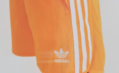 Side view of orange Adidas shorts with the logo visible.