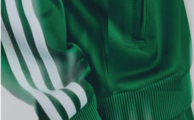 Detail of a green Adidas track jacket with white sleeve stripes.
