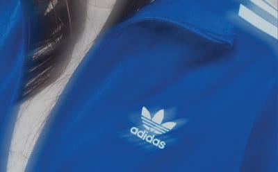 Part of a blue Adidas track jacket with a logo on the chest.