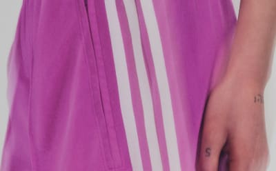 Person in a purple Adidas track pants with white stripes.