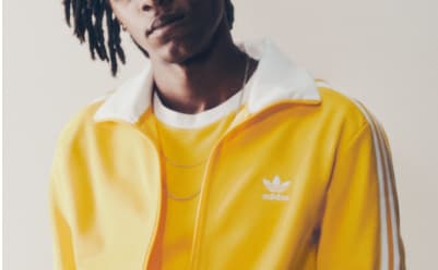 A man with blonde hair wearing a yellow adicolor tracksuit pictured from the neck up.
