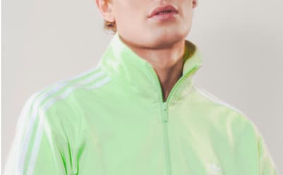 A man with black hair wearing a light green adicolor tracksuit pictured from the neck up.